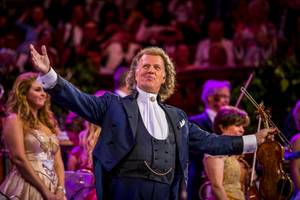 André Rieu dirigiert Orchester auf der Bühne mit ausgebreiteten Armen bei Konzert