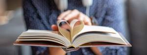 Aufgeschlagenes Buch mit herzförmig gefalteten Seiten in Leserhand