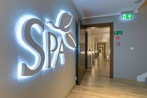 Beleuchtetes SPA-Logo an Wand mit Blick in Wellnessbereich-Flur, Hotel Drei Inseln