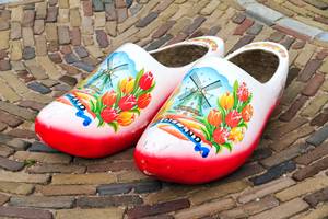 Bemalte Holzschuhe mit Tulpen- und Windmühlenmotiv auf Kopfsteinpflaster in Holland