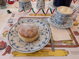 Berliner mit Zuckerguss und Cappuccino auf Kaffeetafel im Hotel Goos Jübek