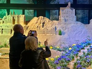 Besucher fotografieren Sandskulptur-Ausstellung BlütenWunder mit Schlossmodellen und Blumen