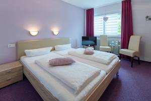 Doppelzimmer mit Doppelbett und rosa Kissen im Hotel Südpfalz Terrassen