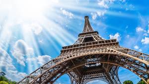 Eiffelturm Paris aus der Froschperspektive vor blauem Himmel mit Sonnenstrahlen