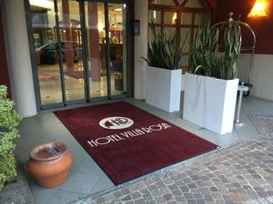 Eingangsbereich Hotel Villa Rosa mit Willkommensmatte und grüner Bepflanzung