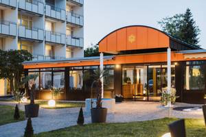 Eingangsbereich Thermenhotel Sonnenhof mit orangefarbenem Vordach am Abend