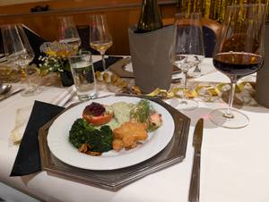 Festlich gedeckter Tisch mit Silvesterball-Menü, Lachs, Gemüse und Weingläsern