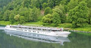 Flusskreuzfahrtschiff MS Elbe Princesse auf der Elbe umgeben von grünem Wald