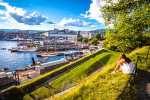 Frau blickt vom Hügel auf Hafen und Skyline von Oslo an sonnigem Tag