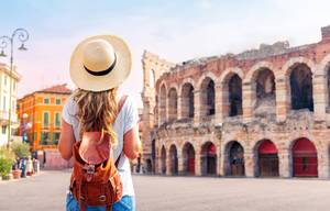 Frau mit Hut und Lederrucksack blickt auf die Arena von Verona in Italien
