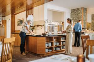 Frühstücksbuffet im Hotel Sonnenhof mit Müsli-Spendern und Gästen am Servicebereich