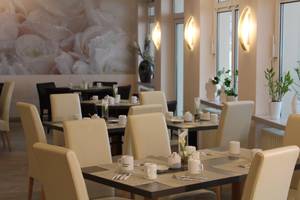 Frühstücksraum im H-Hotel Erfurt mit gedeckten Tischen und cremefarbenen Stühlen