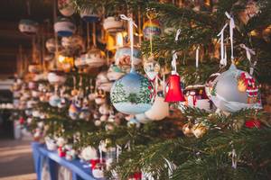 Handbemalte Christbaumkugeln am Weihnachtsmarktstand mit Tannenzweigen