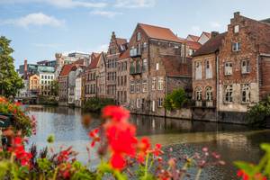 Historische Giebelhäuser am Leie-Kanal in Gent mit roten Blumen im Vordergrund