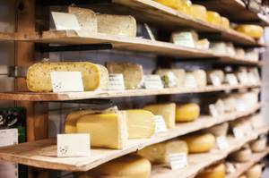 Holländischer Käse in Regalen mit Holzbrettern auf traditionellem Käsemarkt