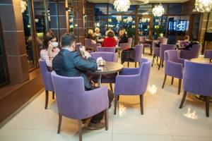 Hotelbar Olymp III Kolberg mit lila Sesseln und Gästen bei Kaffee