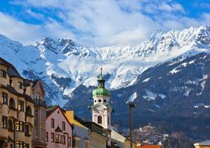 Innsbrucker Altstadt mit Stadtturm vor schneebedeckten Alpengipfeln im Winter