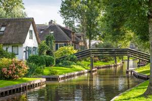 Kanal mit Holzbrücke und reetgedeckten Häusern in Giethoorn, Niederlande