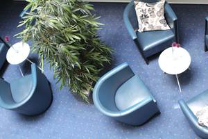 Lobby-Lounge des H+ Hotels Erfurt mit blauen Sesseln, Pflanze und Beistelltischen