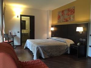 Modernes Doppelzimmer mit Doppelbett, Nachttischlampen und Bad im Hotel Italien