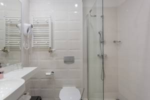 Modernes Hotelbad mit Dusche, Handtuchheizkörper und WC im Hotel Koral Live