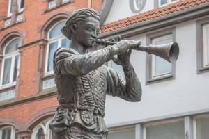 Rattenfänger-Statue mit Flöte vor historischer Fassade in Hameln