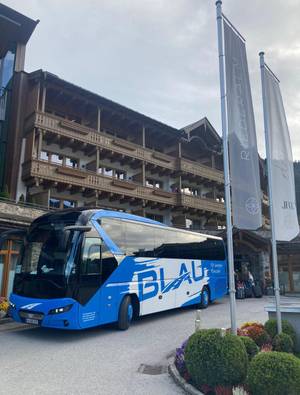 Reisebus von BLAU Touristik vor alpinem Hotel Riederalm in Österreich