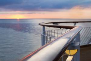 Reling eines Kreuzfahrtschiffs bei Sonnenuntergang über ruhiger See