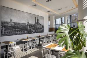 Restaurantbereich im Hotel Arcotel Onyx Hamburg mit Wandgemälde und Bistrotischen