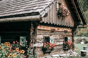Rustikale Almhütte mit Blumenschmuck und Sonnenblumen in den österreichischen Bergen