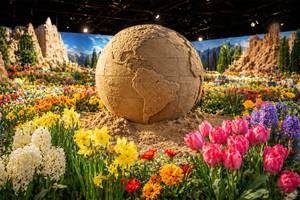 Sandskulptur Weltkugel inmitten bunter Frühlingsblumen bei Blütenwunder-Ausstellung