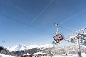Sessellift zur Bergeralm im Wipptal mit Skifahrern vor verschneitem Alpenpanorama