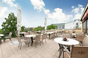 Sonnige Dachterrasse eines Hotels in der Südpfalz mit Tischen und Blick ins Grüne