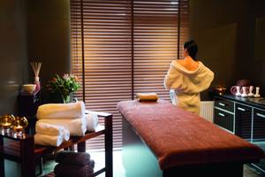 Spa-Bereich im Olymp III Resort mit Massageliege und Frau im Bademantel