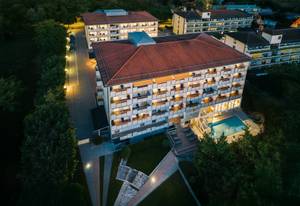Thermenhotel Sonnenhof bei Nacht mit beleuchtetem Pool und Balkonen aus der Luft
