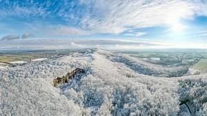 Winterlandschaft im Weserbergland mit schneebedecktem Wald und Felsklippe aus der Luft