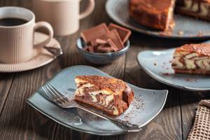 Zebrakuchen mit Schokolade und Kaffee auf rustikalem Holztisch serviert