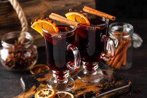 Zwei Gläser Glühwein mit Zimtstangen und Orangenscheiben, weihnachtlich dekoriert